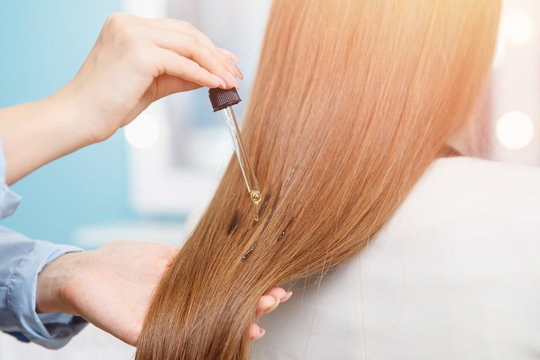 Close-up drop of oil restore and recovery hair is applied to head bulbs. hairdresser spa salon.