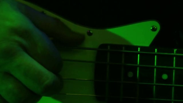 The hand of a man plays bas-guitar.