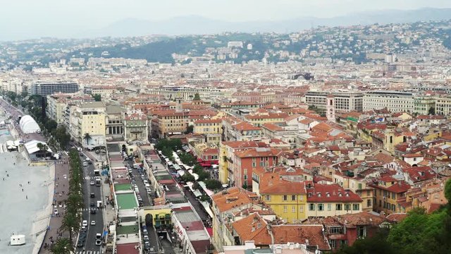Panoramic shot of French city Nice with its luxury houses and people walking on the beach on spring day. Right to left pan real time establishing shot