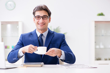 Young handsome businessman drinking coffee in the office 