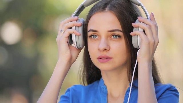 Cute woman listening to music outdoor with headphones, slow motion