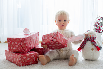 Cute toddler boy, sweet baby, opening presents at home
