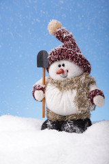 Happy snowman with shovel in snow