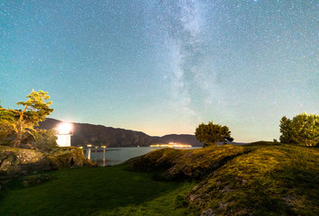 Beautiful Night Sky Milky Way Stars Galaxy with Lighthouse on Ocean Water Coast in Norway Scandinavia