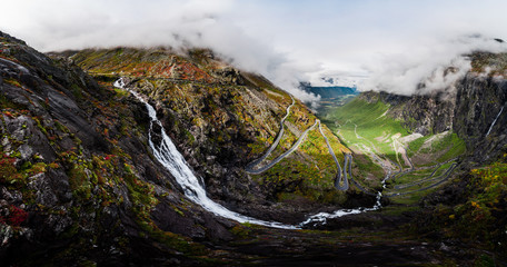 Aerial Panorama View of Trollstigen Road in Norway with Rushing Waterfall and Mountains and Traffic with Clouds and Fog