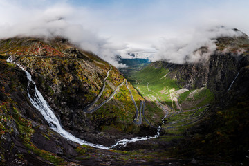 Aerial Panorama View of Trollstigen Road in Norway with Rushing Waterfall and Mountains and Traffic with Clouds and Fog