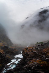 Foggy Mountain View in Norway with River Waterfall off cliff and Clouds with Hazy Atmosphere