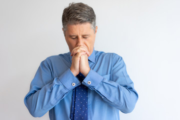Stressed business leader having troubles. Focused Caucasian man in formal shirt and tie praying...