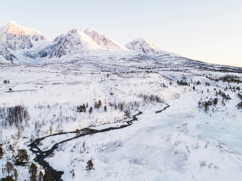 Snow Covered Field And Snow Capped Mountains