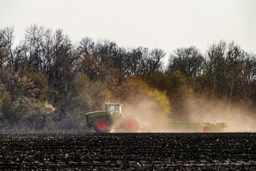 Agricultural tractor with seeder is working in the field. Agrotechnical event.