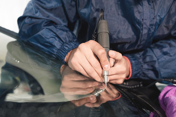 Close up Car glaze worker fixing and repairing a windshield or windshield of a car at a garage...