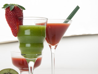 Tres copas de cristal con zumos de tomate y kiwi decorados con un fresón