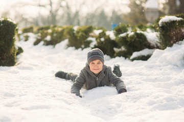 Fototapeta na wymiar A boy in winter clothes jumps into the snow