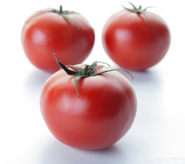 Tres tomates en primer plano con sus hojas sobre un fondo blanco 3
