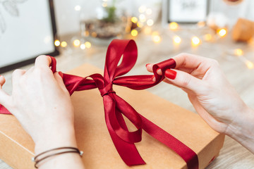 Woman wrapping present in paper with red ribbon.