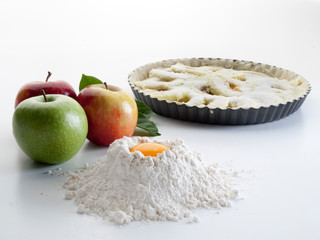 Pastel de manzana horneado junto a manzanas crudas, harina y huevo, vistos frontalmente 4
