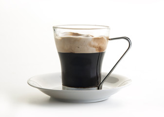 Taza de cristal con café capuchino en su interior visto frontalmente