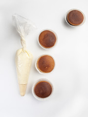 Cuatro madalenas y una manga pastelera vistos cenitalmente