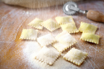 Obraz na płótnie Canvas Raw natural ravioli sprinkle with flour on a wooden table at the time of manufacture