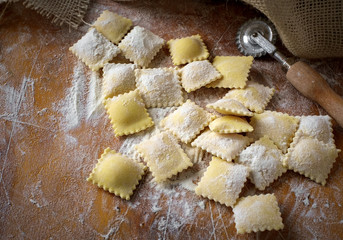 Preparing fresh natural ravioli on wooden kitchen table, traditional Italian pasta