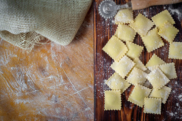 Preparing fresh homemade ravioli at the kitchen table with flour. Top view