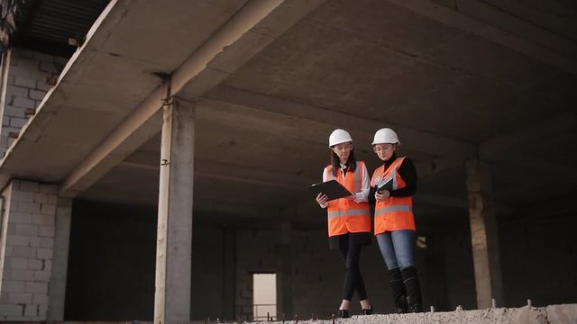 Two women inspectors to inspect and check the construction plan at the construction site.