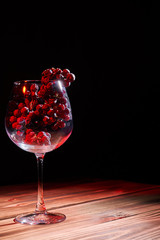 A bunch of ripe grapes in a glass glass glass on a wooden table and a black background