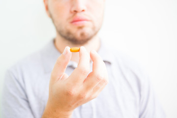 man holding an orange pill with his fingers