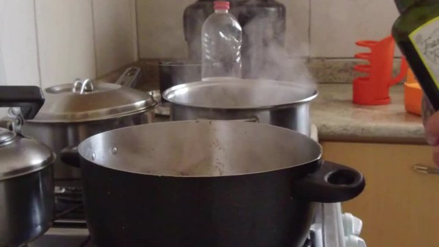 Mo&ccedil;a despejando &oacute;leo em uma panela 