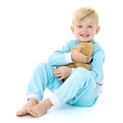 Little boy in pajamas with a teddy bear.