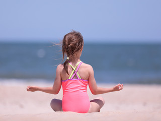 Fototapeta na wymiar Little girl practicing yoga on Rehoboth beach