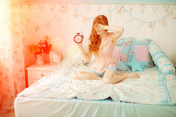 Fototapeta na wymiar Cute young girl in nice children's bedroom with alarm clock