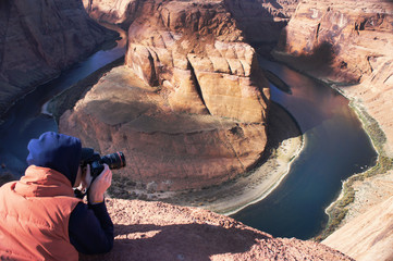 A photographer is taking pictures of Horseshoe Bend in Arizona, USA 