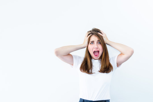 Horrible, stress, shock. Young emotional suprised woman looks at camera, clasping head in hands and opening her mouth isolated on white background. Human emotion, facial expression concept. Copy space