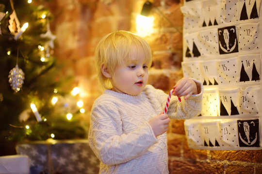 Happy little boy takes sweet from advent calendar on Christmas eve