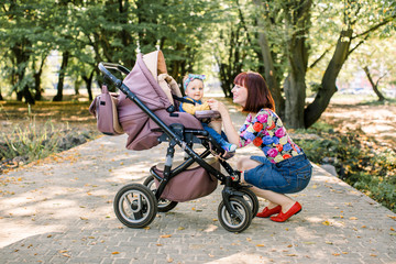 Young mother looking at her child in a baby stroller