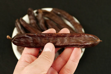 carob fruit of a man's hand,


