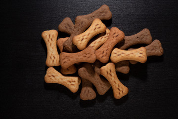 Bone shaped dog cookies or treats, on dark wood background