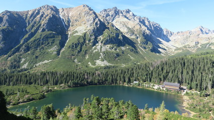 Naklejka na ściany i meble Poprad pleso and Tatra peaks visible from the back. A popular place from which many tourists embark on high mountains. Beautiful nature, blue sky and unparalleled peaks.