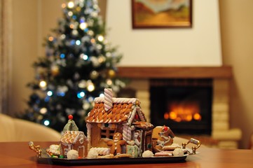 Homemade gingerbread house, gingerbread man, Christmas tree and fireplace in a real room interior