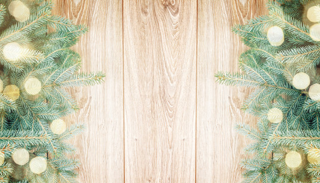 blue fir tree border on wooden background with light beams and copy space