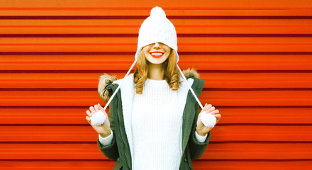 Portrait happy smiling woman in knitted hat and sweater having fun on colorful red background