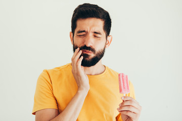 Man have sensitive teeth with ice on white background - obrazy, fototapety, plakaty