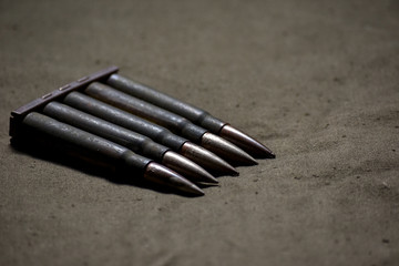 Holder with cartridges 7,92 x 57 - rustic ammos and poncho lies on the wooden background