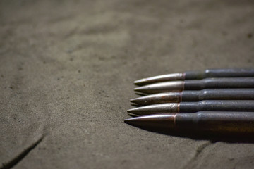 Holder with cartridges 7,92 x 57 - rustic ammos and poncho lies on the wooden background