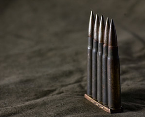 Holder with cartridges 7,92 x 57 - rustic ammos and poncho lies on the wooden background