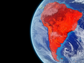 South America from space on model of planet Earth with very detailed planet surface and clouds. Continent highlighted in red.