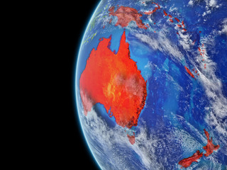 Australia from space on model of planet Earth with very detailed planet surface and clouds. Continent highlighted in red.