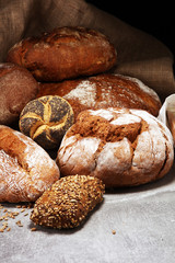 Different kinds of bread and bread rolls on board from above. Kitchen or bakery