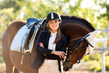 Girl equestrian rider stands near the horse. Horse farm